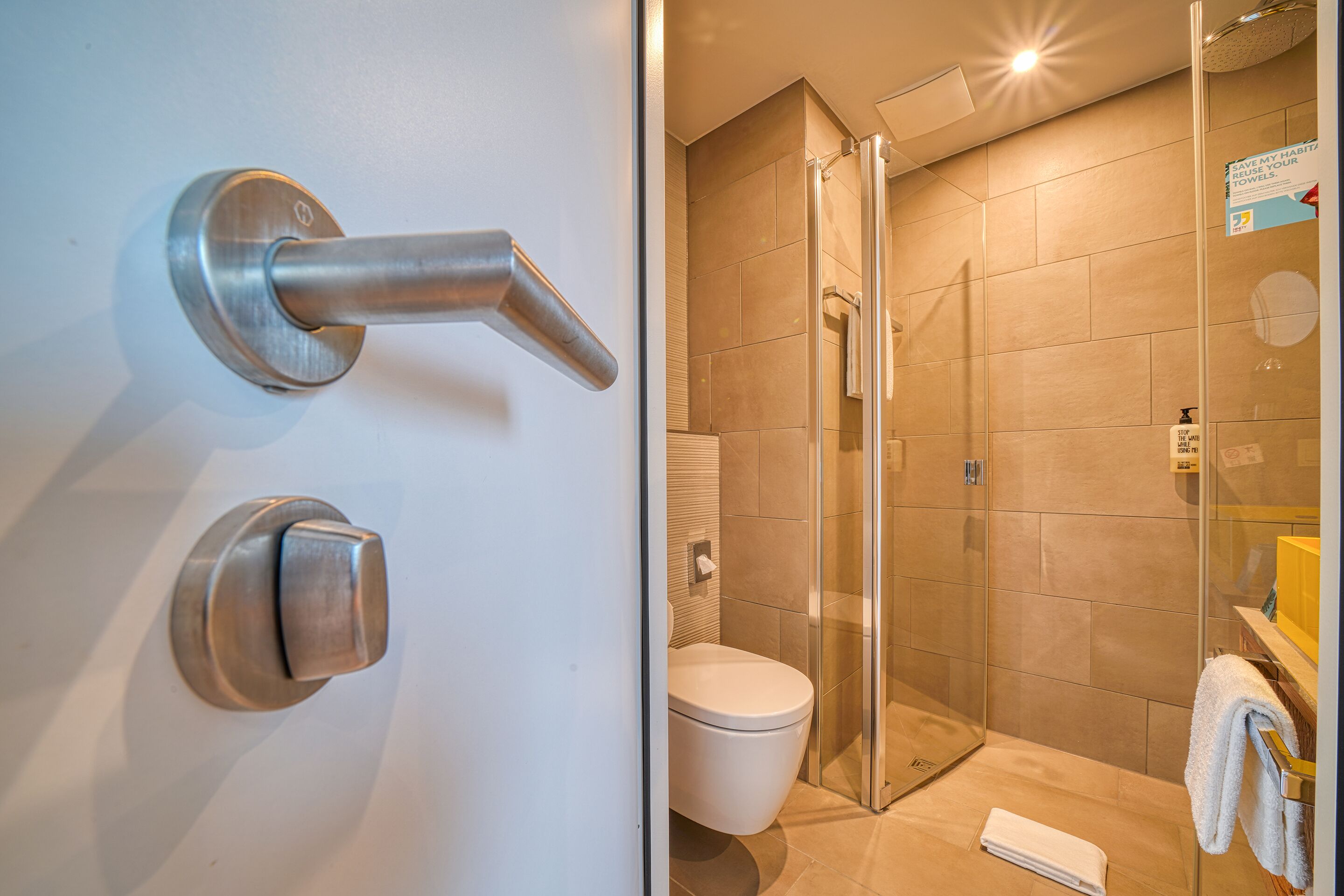 Ein modernes Badezimmer mit Duschkabine aus Glas, einer weißen Toilette und einem Handtuchhalter.