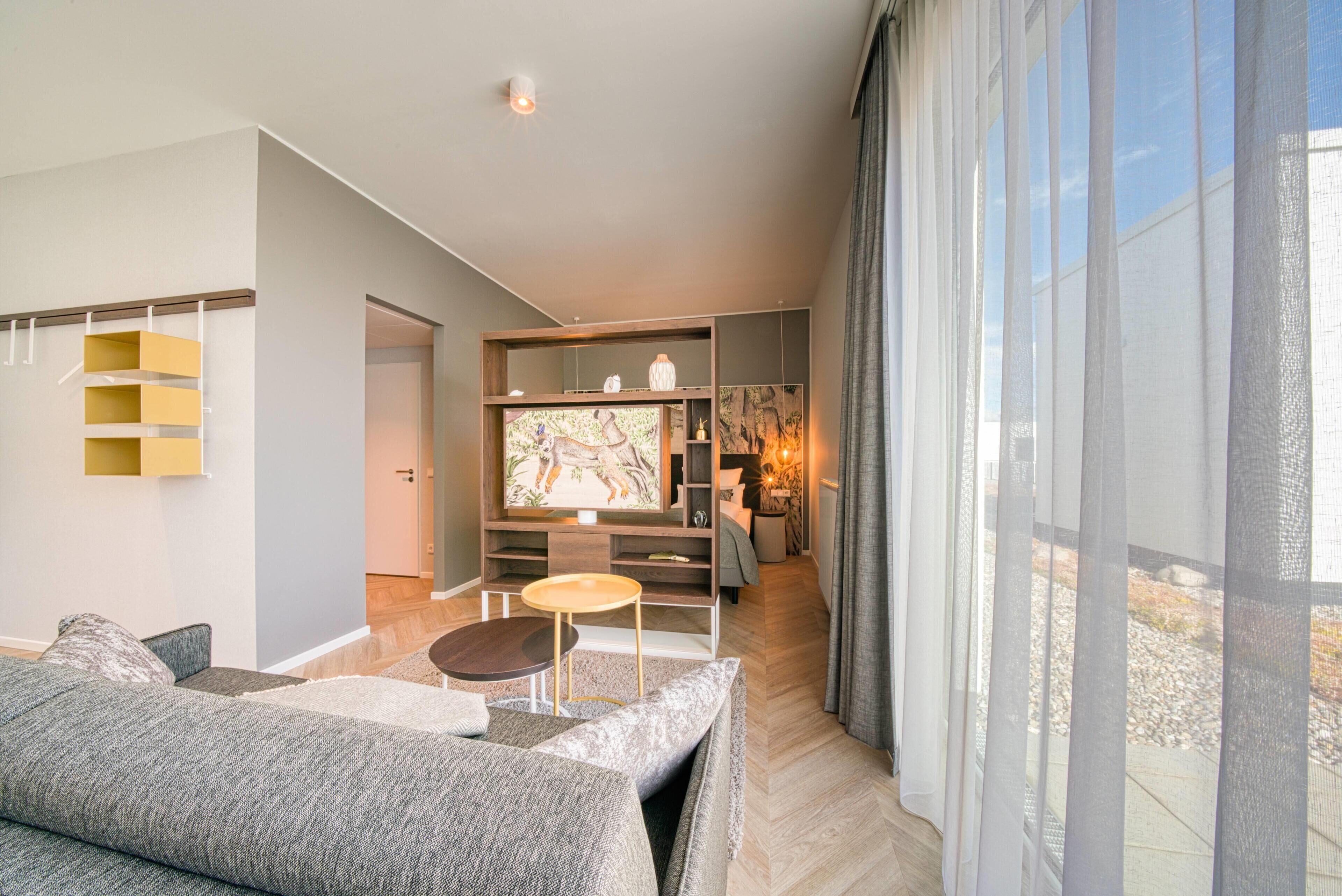 A modern living room with a grey sofa, a small round table, and a TV in the background.