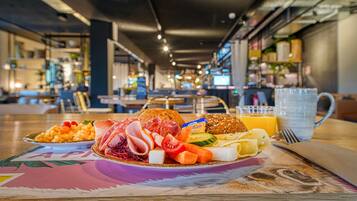 Un bufé de desayuno con diferentes alimentos y una taza de café sobre una mesa en un comedor moderno.