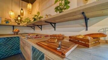 A kitchen counter with bread, a knife, and a cutting board. There are hanging lights and potted plants on shelves above.