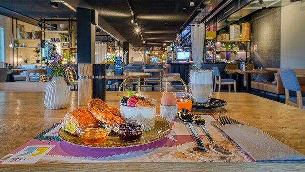 Desayuno con croissants, parfait de yogur y jugo sobre una mesa.