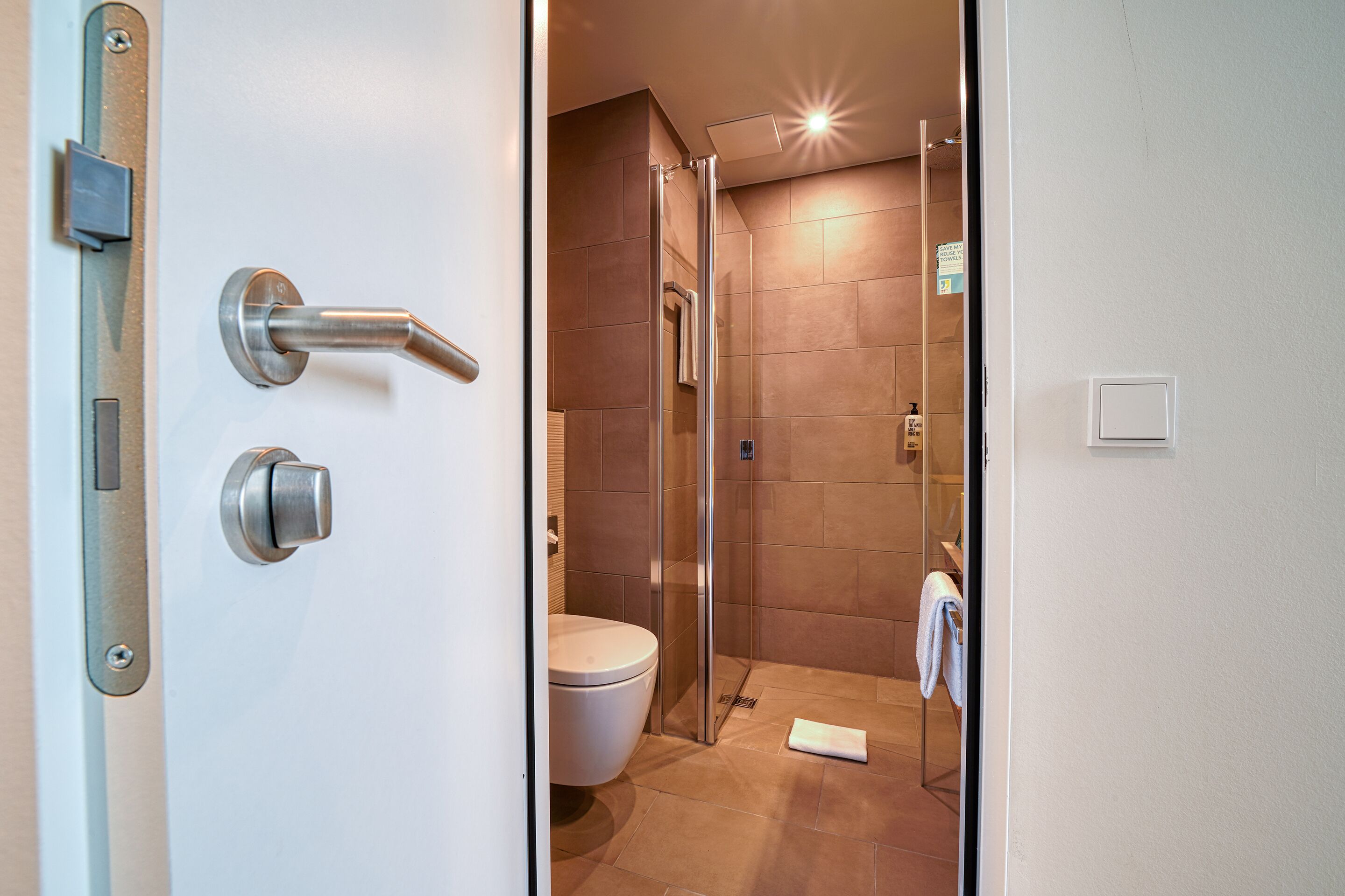 A modern bathroom with a glass shower enclosure, a toilet, and a towel rack.