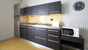 A kitchen with black cabinets, a microwave, and a wall clock. - Italianway - Dogali 17 (Santa Margherita Ligure)