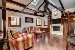 A spacious living room with wooden beams, a fireplace, and a large TV. - Marcopolo-Terrace (Venice)