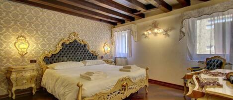 A room with a large ornate bed, wooden beams on the ceiling, and a chandelier.