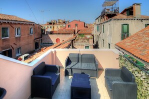 A rooftop terrace with wicker furniture, a satellite dish, and a view of the cityscape. - Marcopolo-Terrace (Venice)