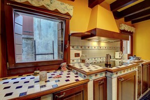 A kitchen with a tiled backsplash, wooden cabinets, and a window with a decorative valance. - Marcopolo-Terrace (Venice)