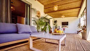 Una sala moderna con piso de madera, un sofá púrpura, una mesa de centro y varias plantas.