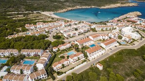 An aerial view of a coastal resort with villas, a beach, and a marina.