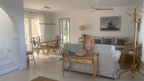 A spacious living area with a dining table and chairs, a sofa, a floor lamp, and a ceiling fan.