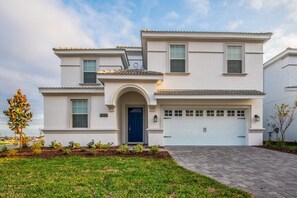 Une maison à deux étages avec une porte bleue, un garage et une pelouse bien entretenue.