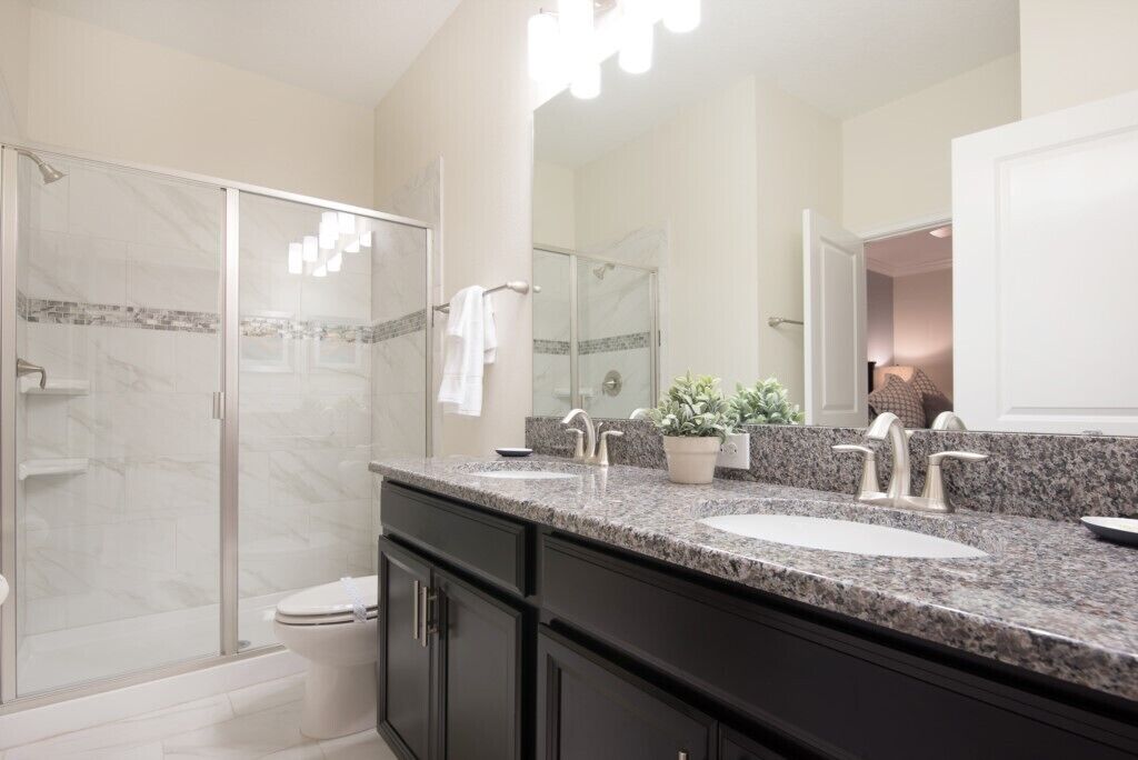 A modern bathroom with a glass-enclosed shower, a double sink vanity, and a large mirror.