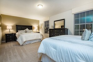 Une chambre avec deux lits, une commode et un grand miroir.