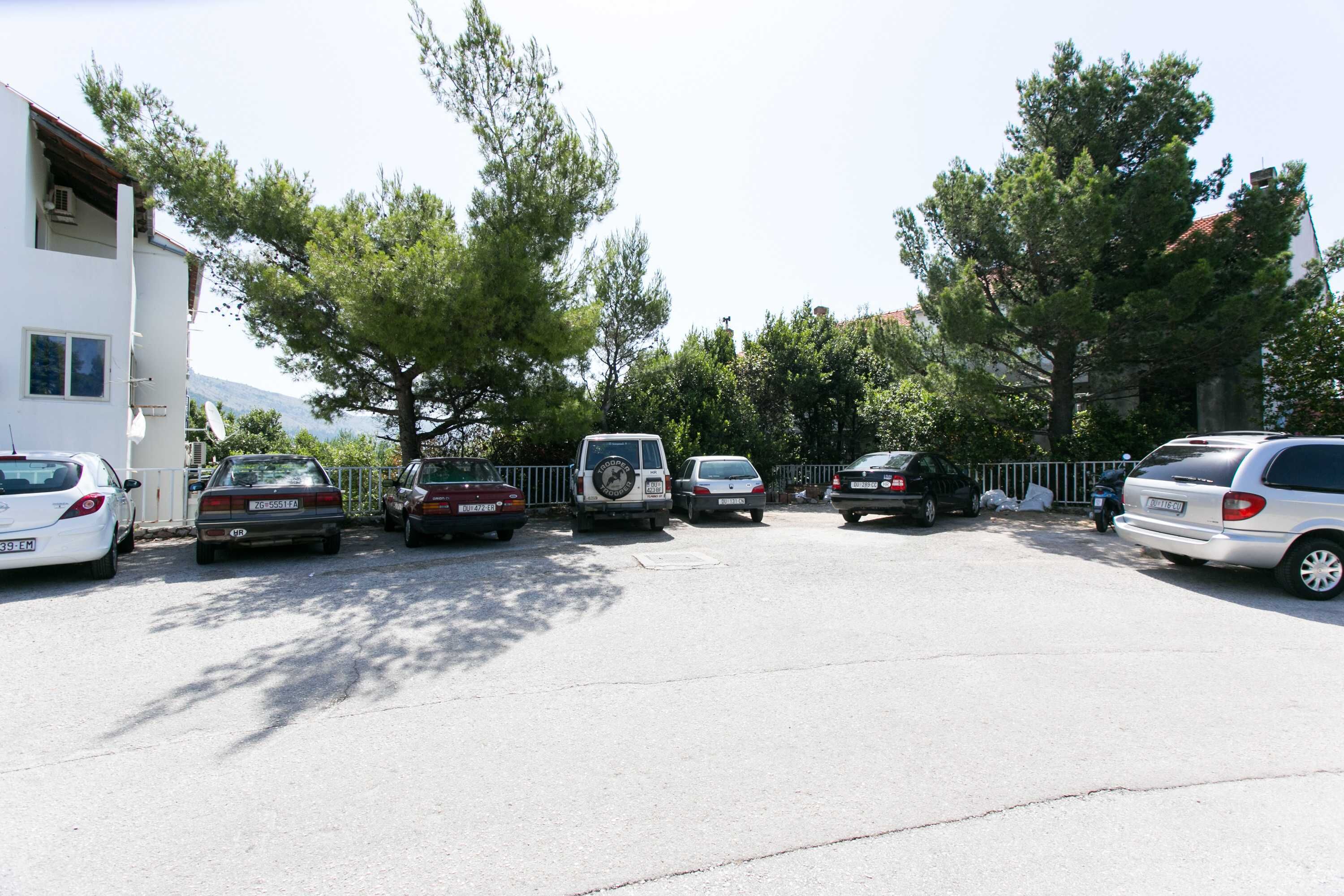 A parking lot with several cars and a white building with a red roof.