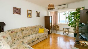 A living room with a sofa, a television, and a potted plant. - Apartment Bor (Dubrovnik)