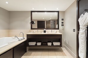 Een bad/douchecombinatie, een bubbelbad, een haardroger, handdoeken