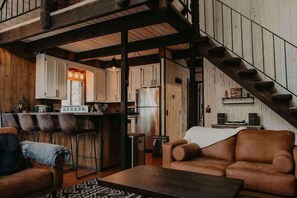 Ein rustikales Interieur mit Barbereich, Holzwänden und einer Treppe.