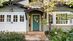 Uma casa com porta verde, portões de garagem brancos e um pequeno alpendre com degraus.