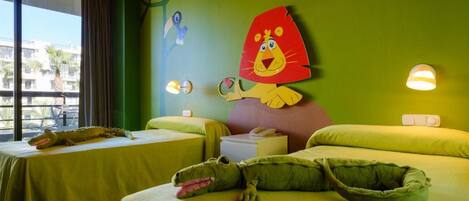 A hotel room with two beds, a large wall mural, and a window with a view of palm trees.