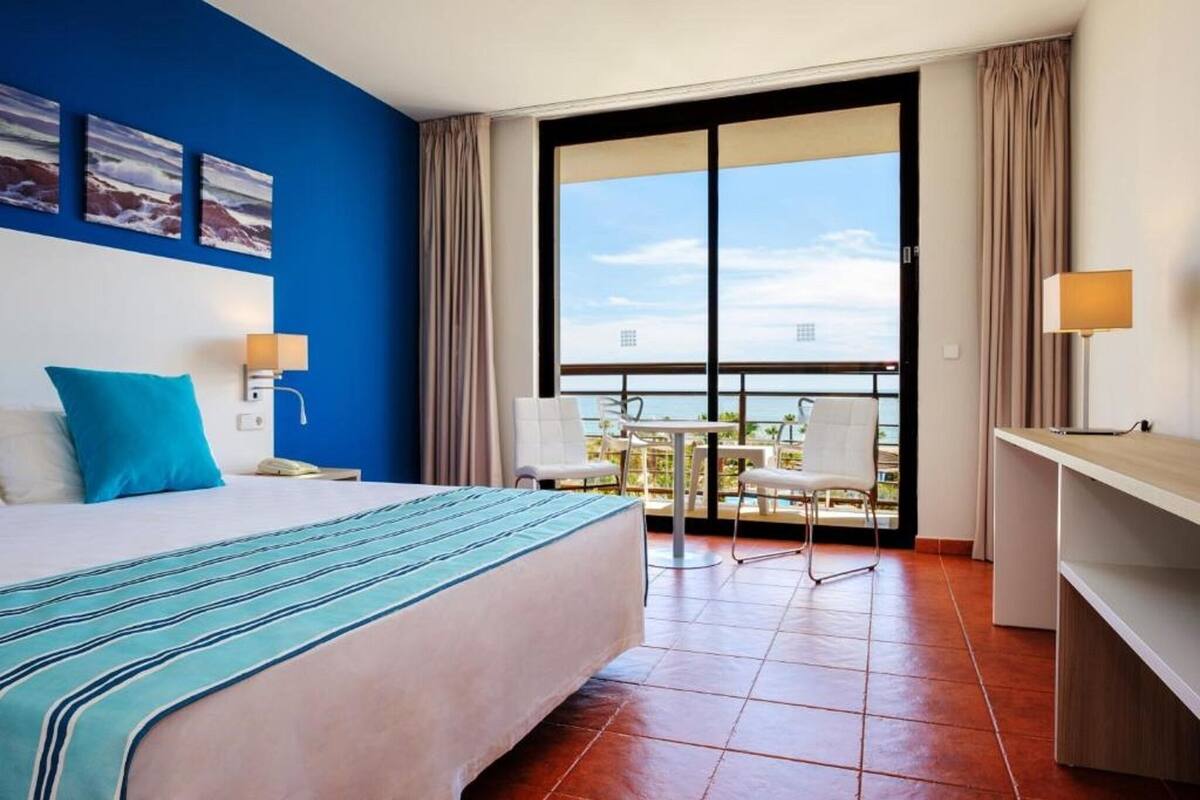 Ein Hotelzimmer mit Bett, Schreibtisch, Balkon und Essbereich.