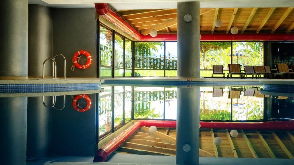 Una piscina con un flotador salvavidas, una escalera y vistas al exterior a través de amplios ventanales.