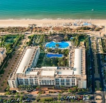 A resort with multiple swimming pools, a beach, and a parking area.