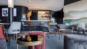 A modern bar area with seating, a television, and a mural on the wall. - Hôtel AKENA TROYES - La Chapelle-Saint-Luc (La Chapelle-Saint-Luc)