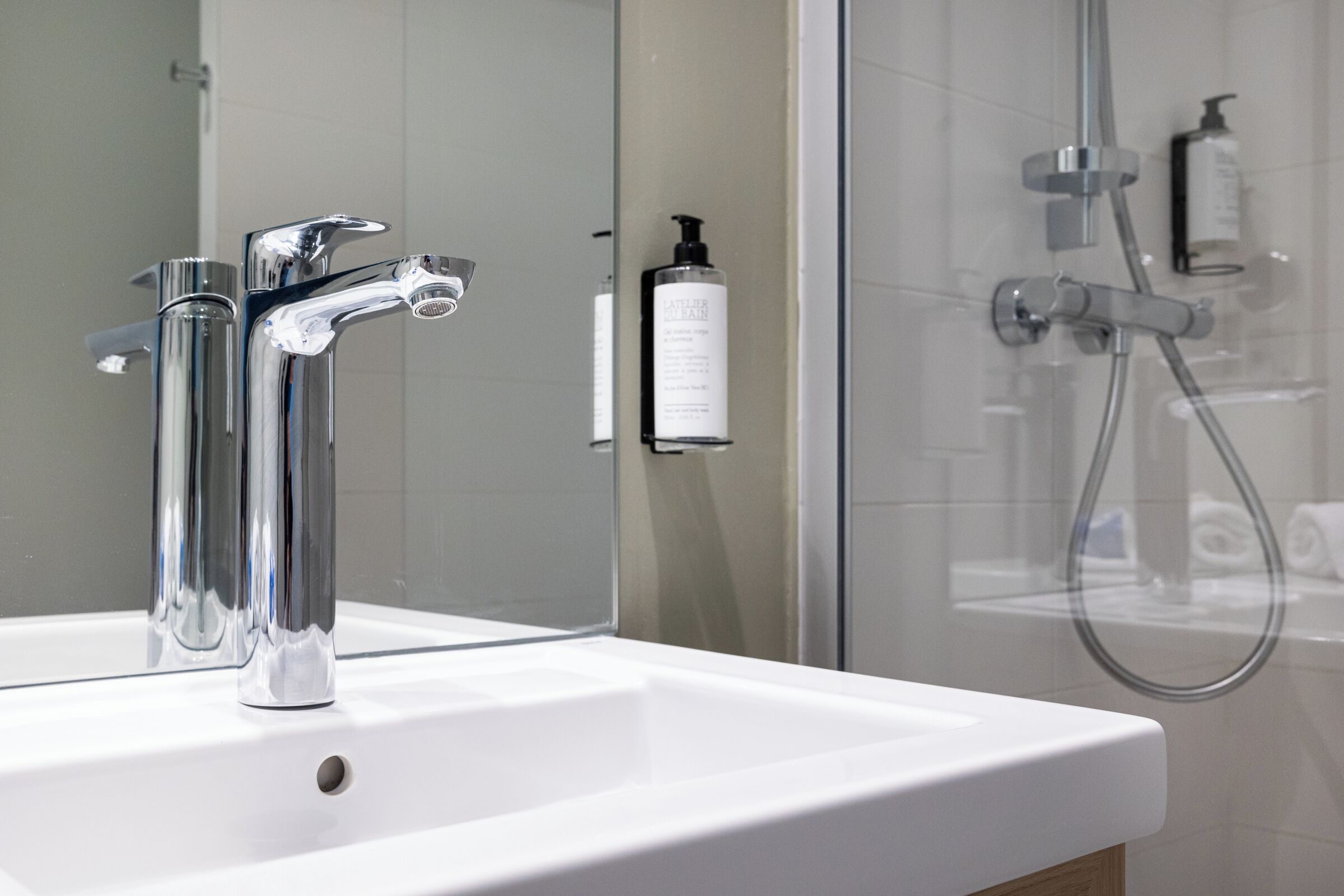Un baño con grifo cromado, lavamanos blanco y cabina de ducha con paredes de vidrio.