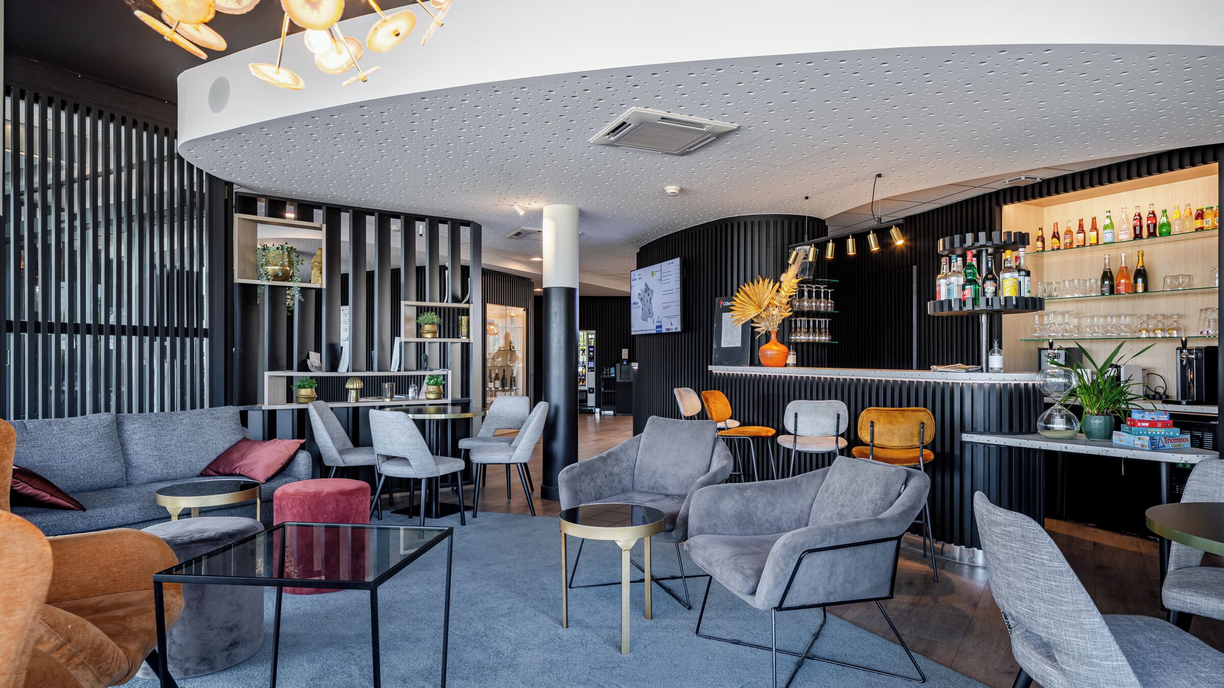 A modern lounge area with seating, a bar, and a television screen.