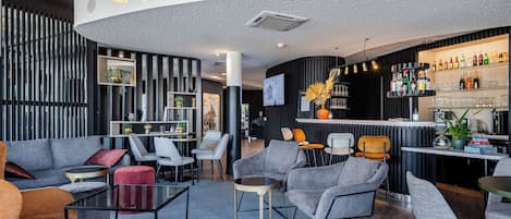 A modern lounge area with seating, a bar, and a television screen.