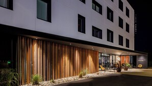 A modern hotel exterior with a flat facade, large windows, and a wooden slatted entrance. - Hôtel AKENA TROYES - La Chapelle-Saint-Luc (La Chapelle-Saint-Luc)