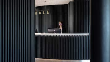 Un comptoir d’accueil avec un ordinateur portable, un mur aux motifs noir et blanc et un plafond doté d’un luminaire.