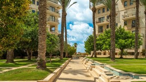 A pathway flanked by palm trees and a building with balconies. - MAMAD - Deluxe 2BD Jaffa Dreams W Pool & Parking (Tel Aviv)