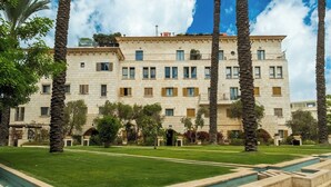A multi-story building with a symmetrical facade, a well-maintained lawn, and a series of steps leading to the entrance. - MAMAD - Deluxe 2BD Jaffa Dreams W Pool & Parking (Tel Aviv)