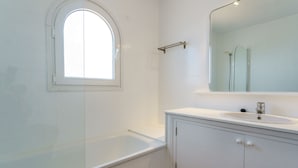 Un baño con bañera, lavamanos y espejo.
