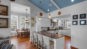 A spacious kitchen with white cabinetry, a central island with bar stools, and pendant lighting. - Intensive Care ~ Steps From the Ocean w/ Golf Cart + Free Attraction Tickets! (Santa Rosa Beach)