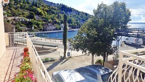 Ein Balkon mit Blick auf eine Küstenlandschaft, einen Parkplatz und ein Gebäude mit einem Schild.