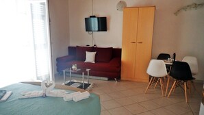 Ein Hotelzimmer mit Bett, Sofa, Fernseher, Kleiderschrank und Essecke.
