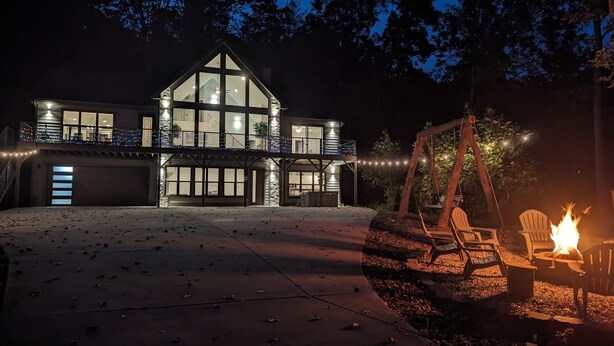 Een moderne woning met een ruim terras, een schommel en een vuurkuil.