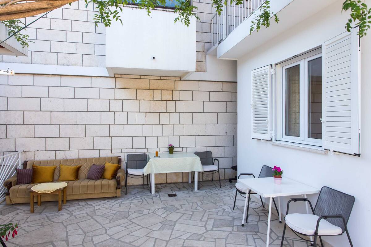 Un espace patio aménagé avec un canapé, deux tables et des chaises.