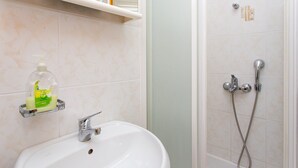 A bathroom with a white sink, a soap dispenser, and a shower with a handheld showerhead. - Guest House Ljubica (Dubrovnik)