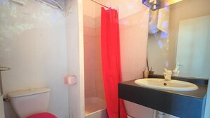 A bathroom with a toilet, sink, and shower curtain. - Meduza Room (Montpellier)
