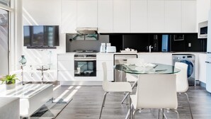 A modern kitchen with white cabinets, a glass dining table, and a built-in oven.