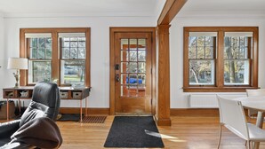 A room with a wooden door, a desk with a lamp, a chair, and a radiator. - Fulton Family Bungalow Pets Welcome. Crib, Highchair, Dog Crate (Minneapolis)