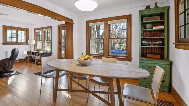 A dining area with a wooden table and chairs, a bowl of fruit, and a green cabinet with decorative items. - Fulton Family Bungalow Pets Welcome. Crib, Highchair, Dog Crate (Minneapolis)