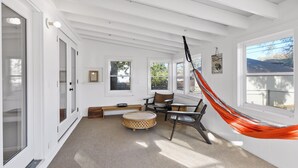 A room with white walls, a hammock, a round table, and two chairs. - Fulton Family Bungalow Pets Welcome. Crib, Highchair, Dog Crate (Minneapolis)