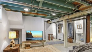 A living room with a television, a wooden bench, a sofa, and a patterned rug. - Fulton Family Bungalow Pets Welcome. Crib, Highchair, Dog Crate (Minneapolis)