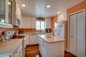 A compact kitchen with white cabinets, a microwave, a toaster, and a refrigerator. - Manatee Lookout (Anna Maria)
