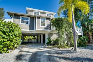 A two-story house with a covered driveway and a palm tree.