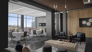 A modern office space with a dining area, comfortable seating, and large windows offering a city view. - AC Hotel by Marriott Columbus Downtown (Columbus)